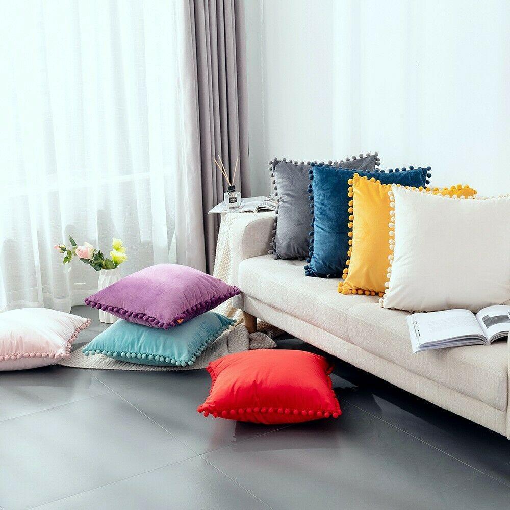 Velvet cushion cover with playful pom pom trim for modern home decor.